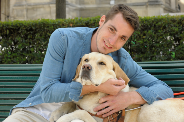 un homme fait un calin a son chien guide d'aveugle