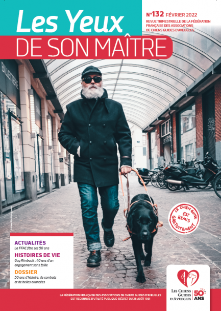 Il s'agit de la couverture de la revue &quot;les yeux de son maître&quot; numéro 132. Gros plan sur un maître de chien guide et son chien guide, labrador noir, en pleine balade dans une rue pavée.